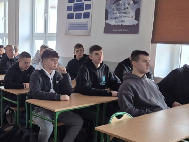 Zdjęcie przedstawia uczniów siedzących w ławkach w klasie, na ścianach plakaty tematyczne.