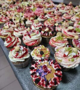 Zdjęcie przedstawia muffinki, udekorowane kremem i ozdobami cukierniczymi.
