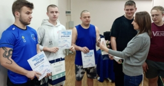 dzien_kobiet_internat4 Zdjęcie przedstawia uczniów trzymających dyplomy turnieju tenisa stołowego. Jeden uczeń trzyma torbę reklamową.