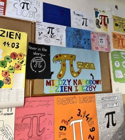 Zdjęcie przedstawia tablicę korkową i ścianę wokół udekorowane kolorowymi plakatami związanymi z tematyką światowego Dnia Liczby Pi.