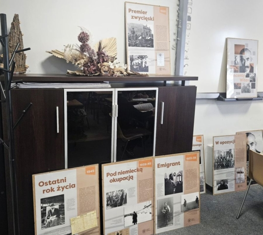 konkurs_historyczny5 Wnętrze gabinetu lub biura. Przy komodzie oraz na ścianie oparte są tablice poświęcone Wincentemu Witosowi.