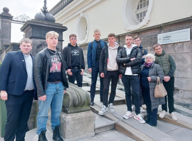 maturzysci_jasna_gora6 Grupa młodzieży, wraz z księdzem i opiekunem wycieczki na dziedzińcu obiektu sakralnego. W tle napis skarbiec.