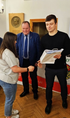 rajd_podhalanski03 Zdjęcie przedstawia uczennicę odbierającą nagrodę rzeczową. W tle tablica pamiątkowa.