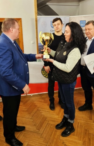 rajd_podhalanski06 Zdjęcie przedstawia 3 osoby dorosłe. Opiekun grupy uczniów biorących udział w rajdzie odbiera puchar z rąk pracownika Urzędu gminy.