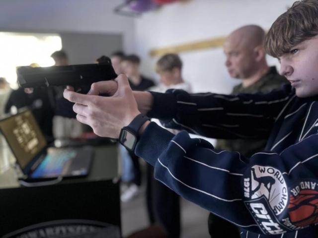 Zdjęcie przedstawia ucznia strzelającego na strzelnicy wirtualnej.