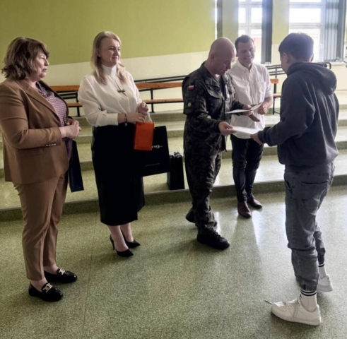 Zdjęcie przedstawia ucznia odbierającego dyplom.