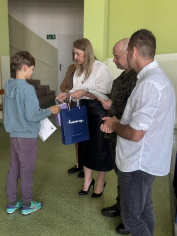 Zdjęcie przedstawia ucznia odbierającego dyplom i nagrodę rzeczową od p. Dyrektor.