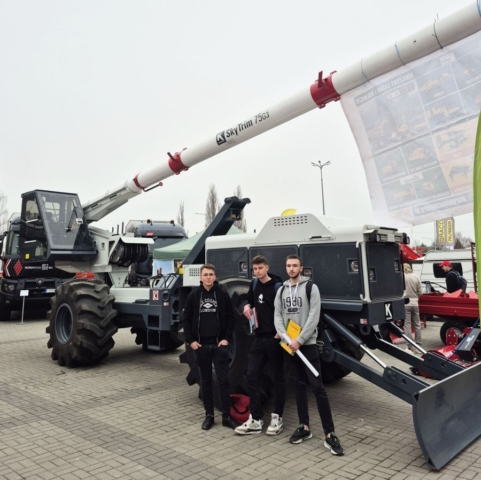 targi_kielce3 Zdjęcie przedstawia trzech uczestników targów, stojących na zewnątrz, przy maszynach rolniczych.