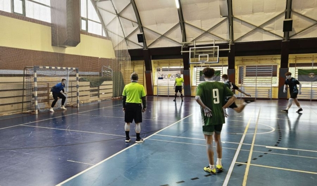 Drużyny sportowe rozgrywające mecz piłki nożnej w hali sportowej.