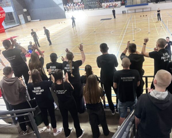puchar_komendanta_policji06 Trybuny sportowe, uczniowie kibicujący zawodnikom biorącym udział w finale turnieju o Puchar Komendanta Policji. W tle tor przeszkód, zawodnicy oraz trybuny po przeciwnej stronie.