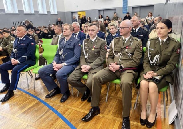Zaproszeni goście, przedstawiciele służb mundurowych oraz władz lokalnych, uczniowie, rodzice i nauczyciele w sali gimnastycznej podczas uroczystego zakończenia roku szkolnego klas maturalnych.