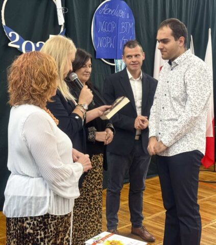Absolwent klasy branżowej odbiera nagrodę książkowa z rąk p. Dyrektor podczas uroczystości zakończenia roku szkolnego klas maturalnych. Towarzyszą p. Wicedyrektor, opiekun klas branżowych i p. wychowawczyni