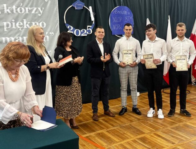 Dyrekcja, wychowawca i opiekun klasy branżowej na uroczystości zakończenia roku szkolnego klas maturalnych w sali gimnastycznej.