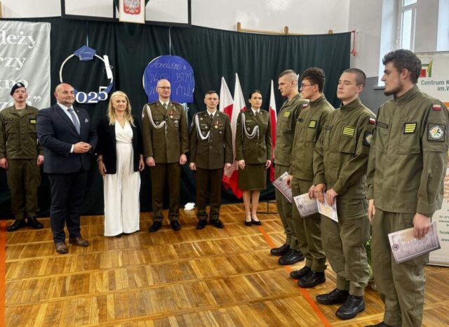 3 przedstawicieli służb mundurowych, p. dyrektor, p. wicestarosta, po prawej stronie 4 kadetów klasy OPW w umundurowaniu podczas uroczystości zakończenia roku szkolnego klas maturalnych. Kadeci trzymają w rękach certyfikaty.