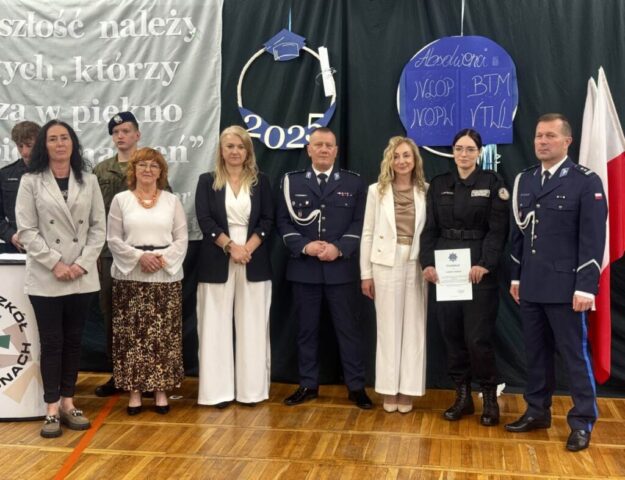 Uroczystość zakończenia roku szkolnego klas maturalnych w udekorowanej sali gimnastycznej. Dyrekcja, wychowawca klasy, przedstawiciele służb mundurowych policji, nauczyciel i uczniowie.