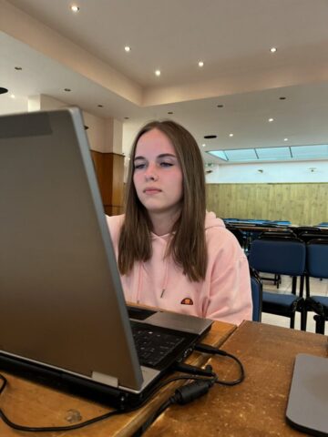grecja_czwarty_piaty_dzien19 Uczestniczka zagranicznych praktyk zawodowych wykonuje prace na komputerze. Siedzi przed ekranem komputera z dużej sali konferencyjnej.