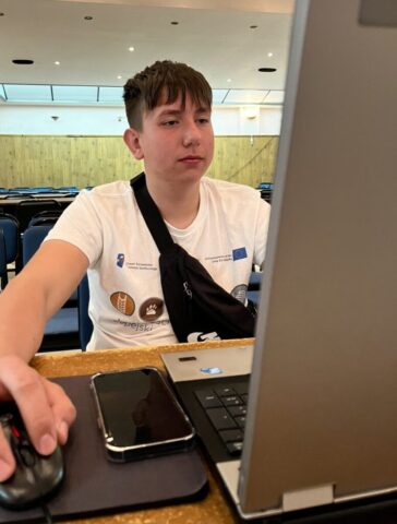 Uczestnik zagranicznych praktyk zawodowych w sali komputerowej. Siedzi przed komputerem i pracuje nad czymś.
