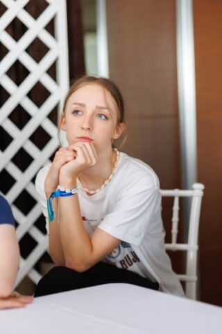 Uczestniczka zagranicznej praktyki zawodowej siedzi na białym krześle w pomieszczeniu.