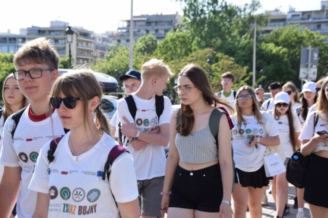 Uczestnicy zagranicznej praktyki zawodowej podczas zwiedzania w centrum miasta. W tle zabudowania i zieleń.