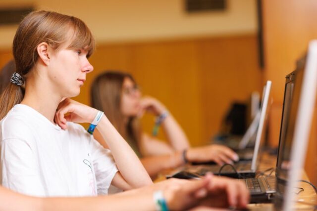 Uczestniczki zagranicznej praktyki zawodowej w pomieszczeniu. Siedzą przy biurkach i patrzą w ekrany laptopów.