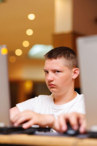 Uczestnik zagranicznej praktyki zawodowej w pomieszczeniu. Siedzi przy biurku i pracuje na laptopie.
