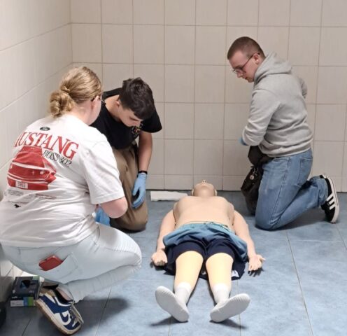 3 uczestników konkursu w pomieszczeniu. Na podłodze leży fantom.
