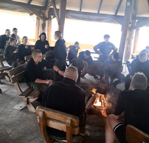 Uczestnicy obozu szkoleniowego podczas ogniska pod wiatą.