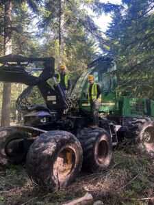 Harwester w lesie. Na harwesterze dwaj uczniowie