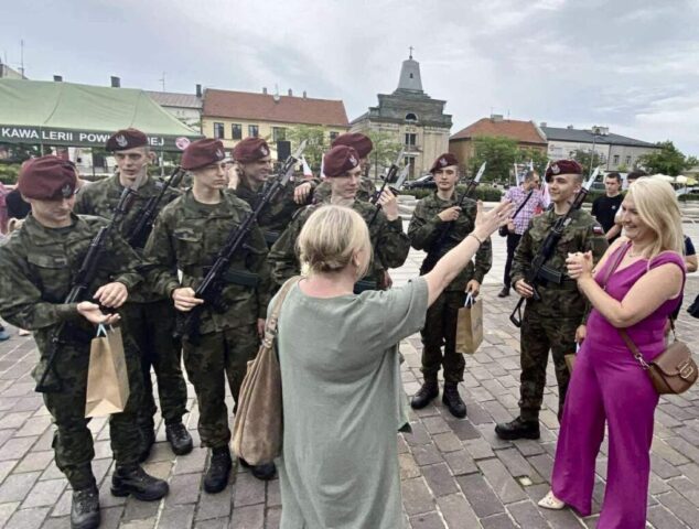 Kadeci OPW, absolwenci ZS CKZ Bujny w umundurowaniu wraz z p. Dyrektor i p. Wychowawczynią na zewnątrz. W tle zabudowania oraz namiot firmowy 25. Brygady Kawalerii Powietrznej.