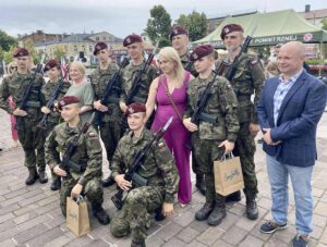 Absolwenci klasy OPW w umundurowaniu wraz z p. Dyrektor, p. Wychowawczynią i opiekunem klas OPW na zewnątrz. Pozują do zdjęcia w trakcie uroczystości złożenia ślubowania po odbytym szkoleniu dobrowolnej zasadniczej służby wojskowej. 