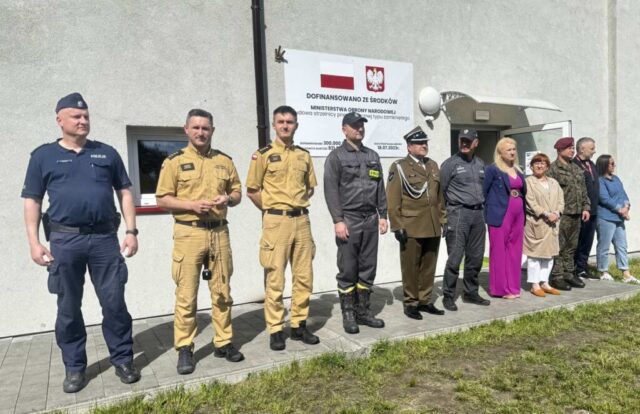 Przedstawiciele służb mundurowych, Dyrekcja szkoły oraz nauczyciele WF przed budynkiem strzelnicy.