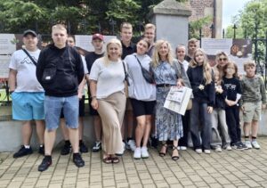 Grupa uczniów wraz z opiekunami na zewnątrz, przed Muzeum Okręgowym w Piotrkowie. 