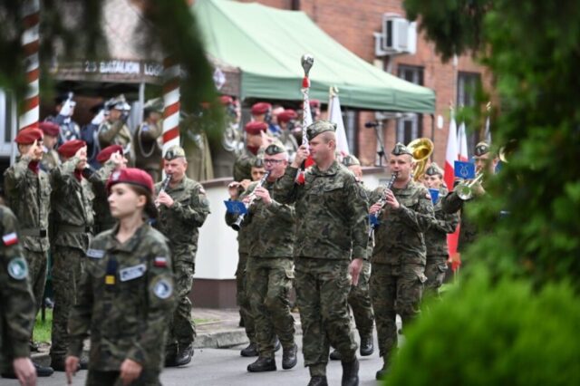 Obchody święta 25. Batalionu Logistycznego. Defilada Żołnierzy. Po lewej stronie namiot i salutujący przedstawiciele służb mundurowych.