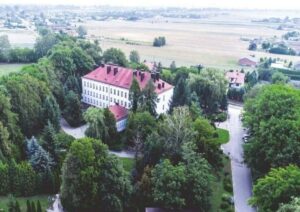Budynek Szkoły ZS CKZ Bujny z lotu ptaka z przyległymi zabudowaniami i terenami zielonymi.