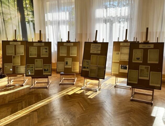 Hol szkoły, sztalugi ze zdjęciami, wystawa zatytułowana Ze szkolnego archiwum.