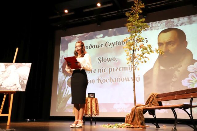 Uczennica w stroju galowym na scenie podczas Narodowego Czytania.
