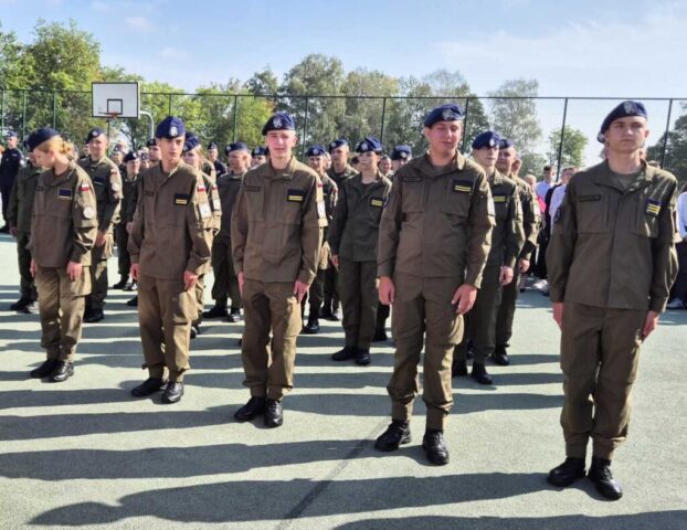 Boisko szkolne Orlik przy ZS CKZ w Bujnach. Uroczystość rozpoczęcia roku szkolnego. Ustawieni w szeregach kadeci klas OPW w umundurowaniu. i beretach.
