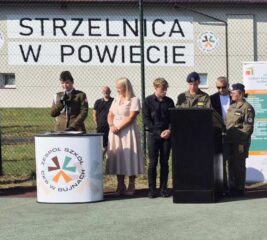 rozpoczecie04 Boisko szkolne Orlik przy ZS CKZ Bujny. Pani Dyrektor, przedstawiciel służb mundurowych, uczniowie klas OPW oraz koordynator OPW. W tle budynek strzelnicy.