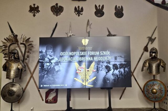 Billboard promujący wydarzenie Ogólnopolskie Forum Szkół "Edukacja obrona młodzieży". Po bokach tarcze, zbroje oraz broń. U góry godła.