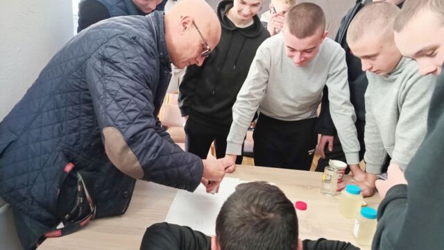 Grupa uczniów wraz z opiekunem. Badają próbki wody.