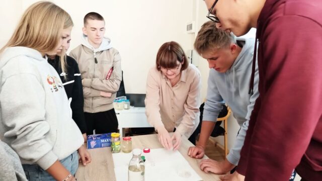 Grupa uczniów wraz z opiekunem podczas badania próbek wody.