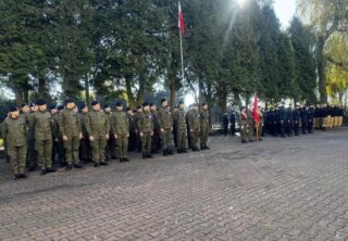 apel_odzyskanie_niepodleglosci03 Dziedziniec szkolny. Uczniowie i poczet sztandarowy podczas apelu. W tle drzewa.