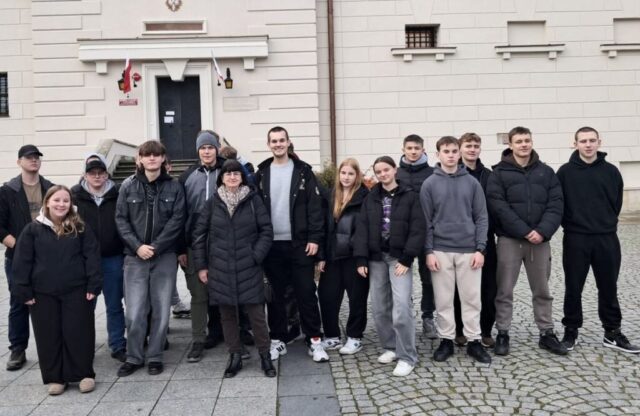 Młodzież wraz z opiekunem na tle budynku muzeum.