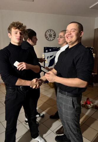 wigilia_internat05 Młodziez w pomieszczeniu składająca sobie życzenia i łamiąca się Opłatkiem.