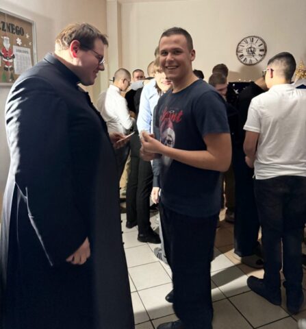 wigilia_internat07 Młodzież i książ w pomieszczeniu. Składają sobie życzenia i łamią się Opłatkiem.