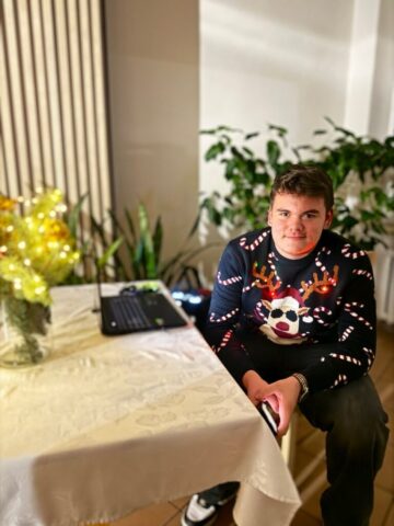 wigilia_internat14 Uczeń siedzący przy stole, na którym jest laptop i dekoracja świąteczna.