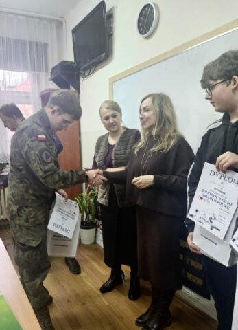 konkurs_zolnierze_wykleci4 Uczeń w umundurowaniu klasy OPW odbiera Dyplom z rąk organizatorów konkursu.