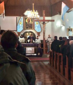 Wnętrze kościoła, przy ołtarzu Ksiądz odprawiający mszę wraz z ministrantami. W kościele zgromadzona młodzież. 