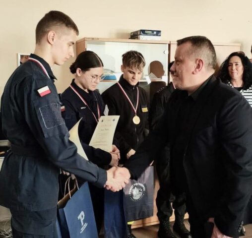 Uczeń odbiera dyplom z rąk organizatora.