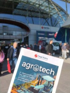 Ulotka targów Agrotech na tle miejsca wystawy. 